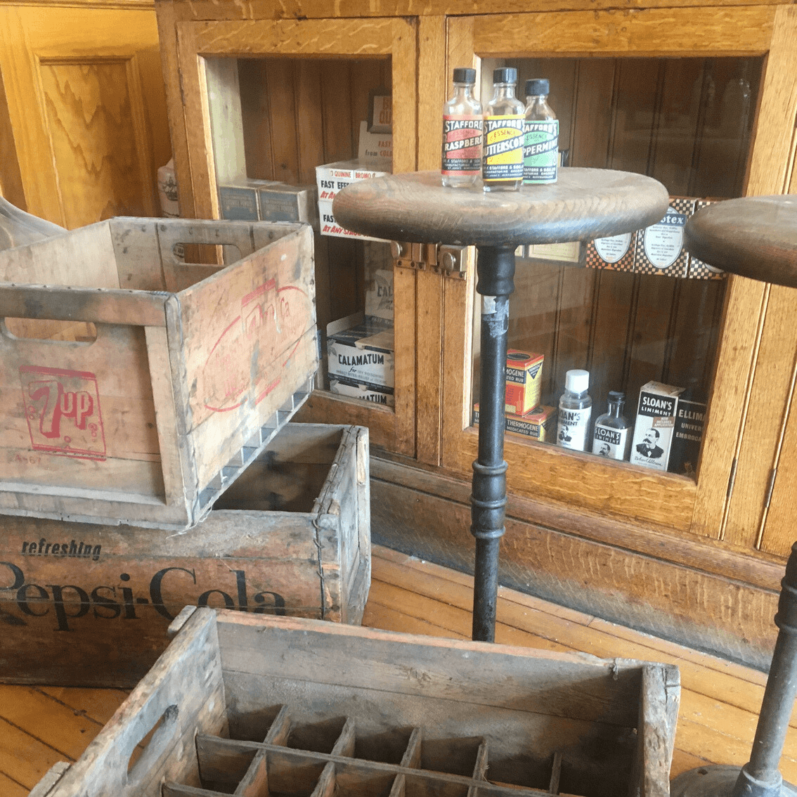 Round counter stool, branded soda bottle crates, and 3 small glass bottles